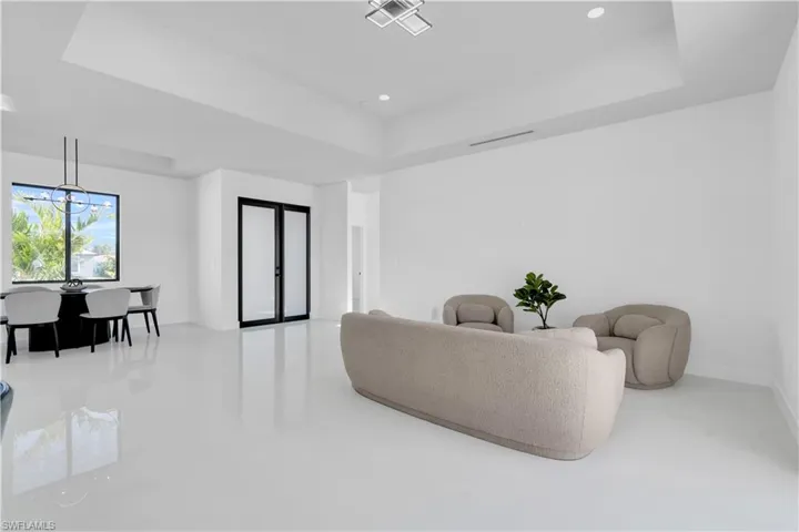 Living area featuring a notable chandelier, baseboards, recessed lighting, visible vents, and a tray ceiling