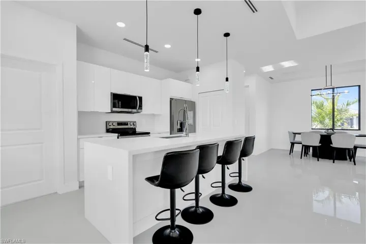 Kitchen with white cabinets, modern cabinets, light countertops, a kitchen breakfast bar, and stainless steel appliances