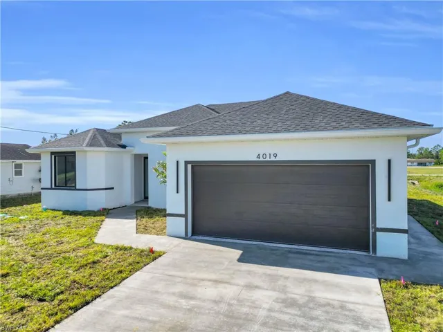 View of front of property with a garage, concrete driveway, stucco siding, and a shingled roof