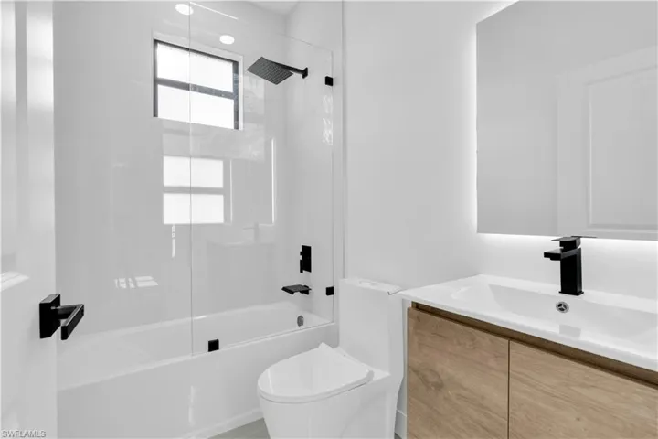Bathroom featuring toilet, shower / bathing tub combination, and vanity