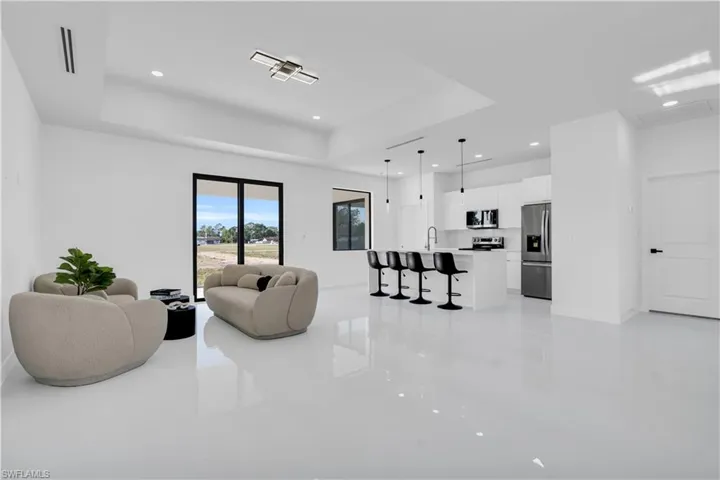 Living area with recessed lighting, light tile patterned floors, a tray ceiling, and baseboards