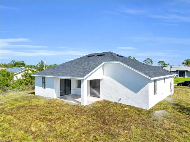 Back of property with a patio area, roof with shingles, stucco siding, and a yard