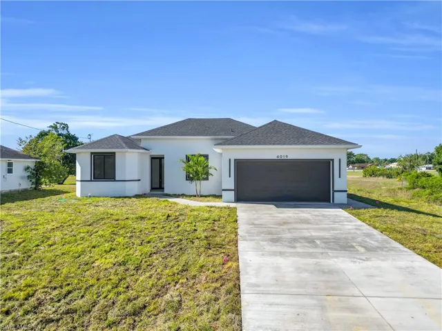 View of front of property with a front lawn, stucco siding, a garage, and concrete driveway