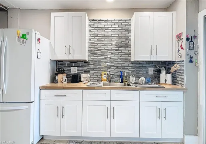 Kitchen featuring white cabinets, white fridge, and tasteful backsplash