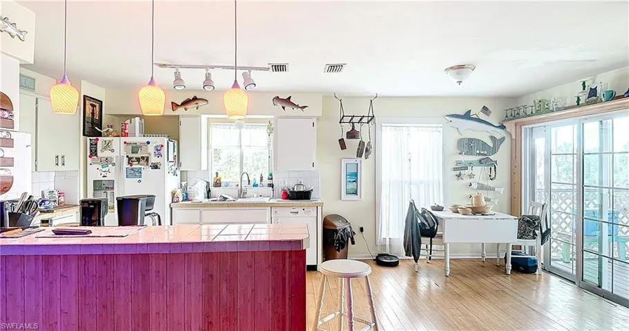 Kitchen featuring light hardwood / wood-style floors, white refrigerator with ice dispenser, tasteful backsplash, and white cabinetry