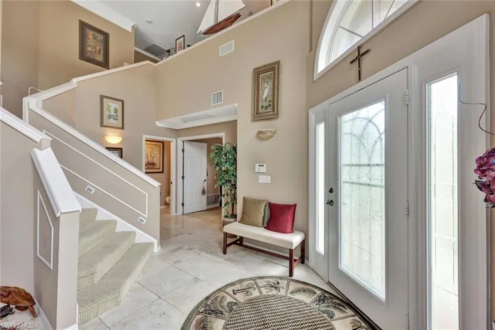 The elegant tiled foyer showcases the etched glass door with sidelights. This view is in to the lower-level Master Suite.