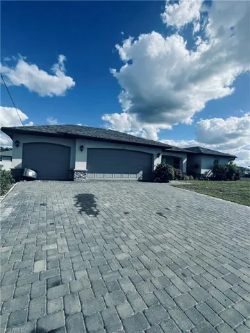 View of front of property with decorative driveway and an attached garage