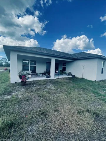 Rear view of house featuring stucco siding and a yard