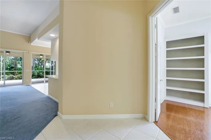 Corridor with crown molding, built in shelves, and light wood-type flooring