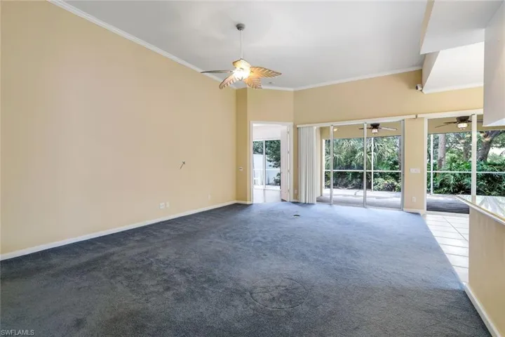 Carpeted empty room featuring ornamental molding and ceiling fan