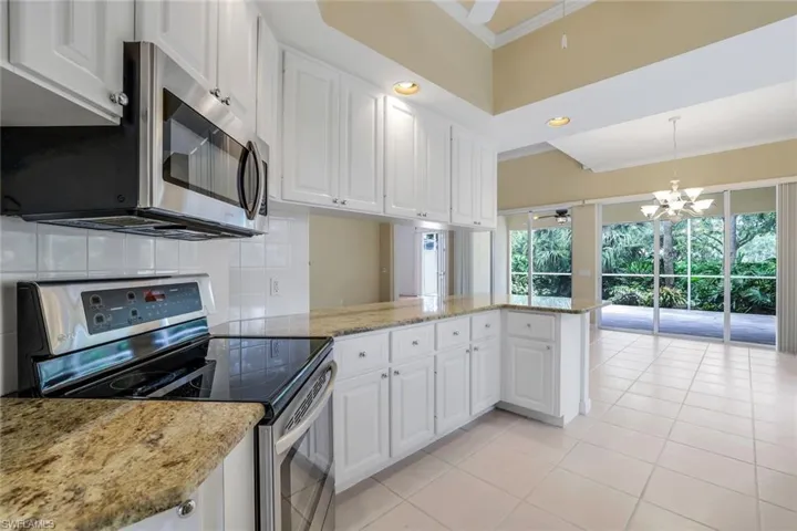 Kitchen with stainless steel appliances, kitchen peninsula, backsplash, and white cabinetry