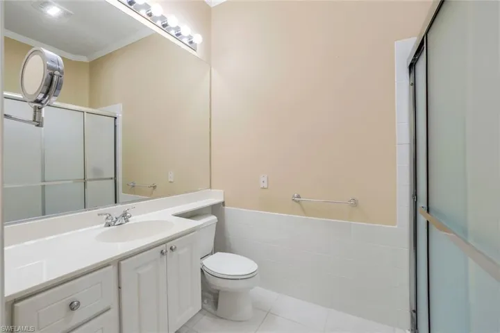 Bathroom with crown molding, tile flooring, tile walls, large vanity, and toilet