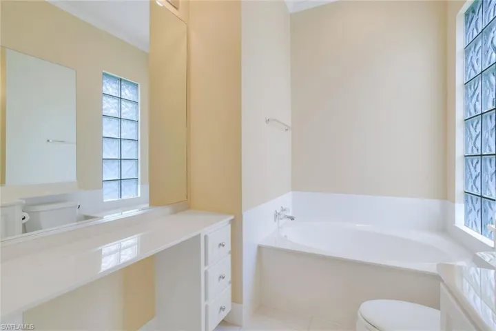 Bathroom featuring toilet, a washtub, tile flooring, ornamental molding, and vanity