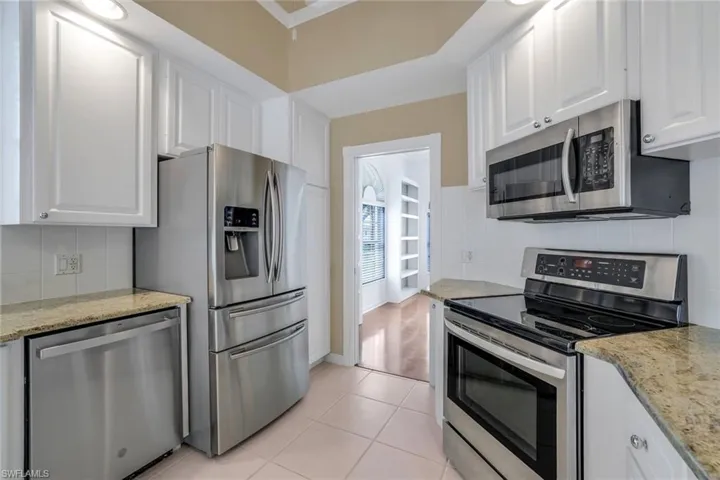 Kitchen with appliances with stainless steel finishes, white cabinetry, and light tile floors