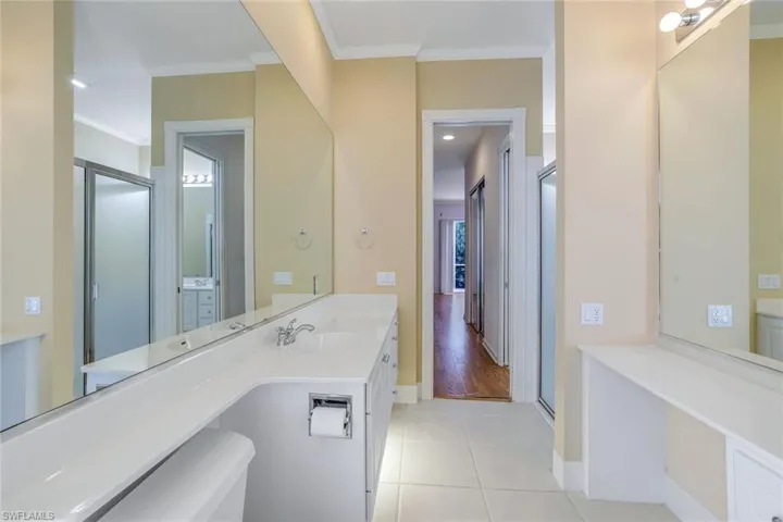 Bathroom with tile flooring, vanity, toilet, and crown molding