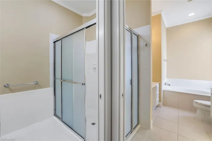 Bathroom with tile flooring, ornamental molding, toilet, and plus walk in shower