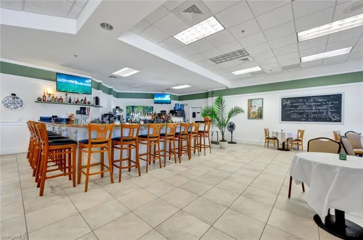 Dining area featuring light tile floors, a paneled ceiling, and indoor bar