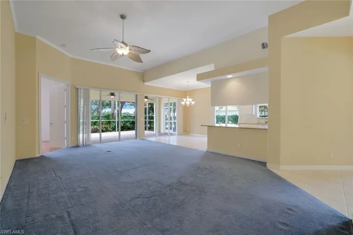 Unfurnished room featuring tile flooring, crown molding, and ceiling fan with notable chandelier