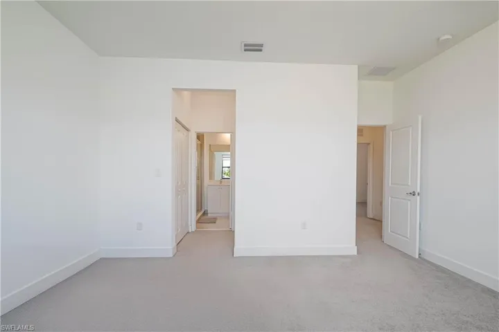Unfurnished bedroom featuring light colored carpet and ensuite bathroom