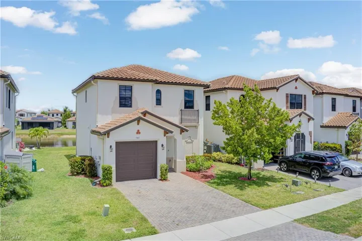 Mediterranean / spanish-style house featuring a tile roof, decorative driveway, stucco siding, a garage, and a front lawn