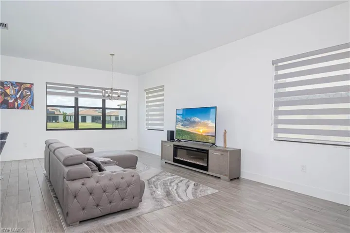 Living area with light wood-style floors, a glass covered fireplace, and a chandelier