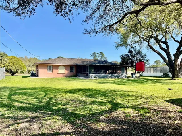 View of HALF ACRE backyard with screened lanai and fenced dog run.