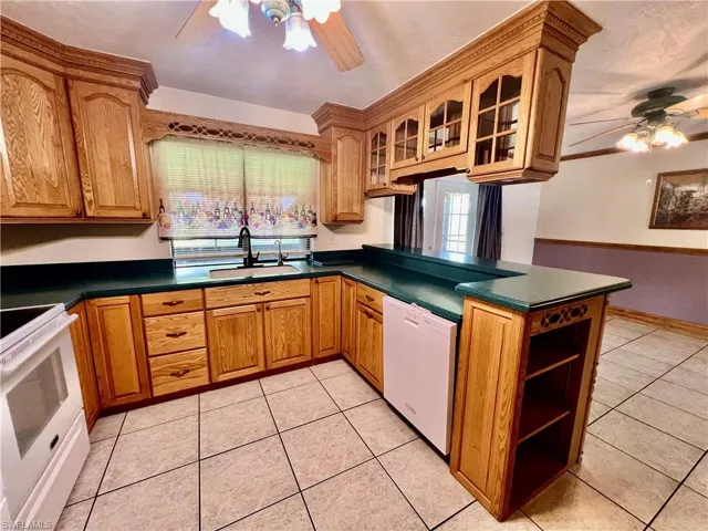 Kitchen featuring a ceiling fan, solid surface tops, breakfast bar, pantry and appliances.