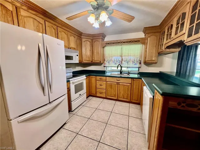 Kitchen featuring a ceiling fan, solid surface tops, breakfast bar, pantry and appliances.