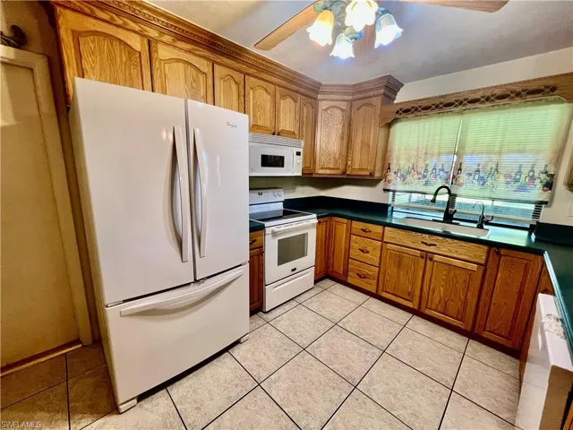 Kitchen featuring a ceiling fan, solid surface tops, breakfast bar, pantry and appliances.