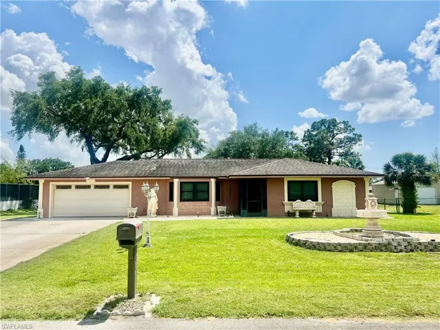 Ranch-style home featuring a front yard, driveway, stucco siding, and an attached garage