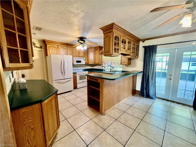 Kitchen featuring a ceiling fan, solid surface tops, breakfast bar, pantry and appliances.