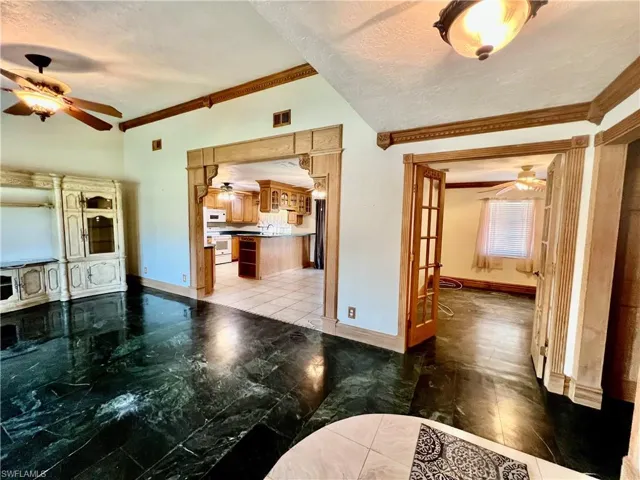 Living room with marble floors, a ceiling fan, ornamental molding, and cathedral ceilings.