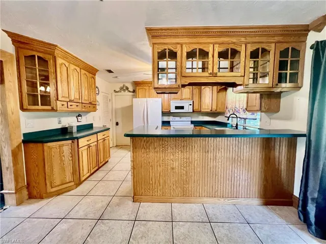 Kitchen featuring a ceiling fan, solid surface tops, breakfast bar, pantry and appliances.