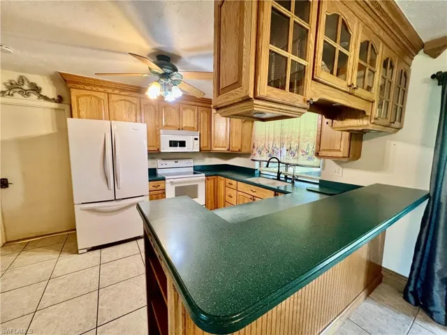 Kitchen featuring a ceiling fan, solid surface tops, breakfast bar, pantry and appliances.
