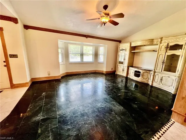 Living room with marble floors, a ceiling fan, ornamental molding, and cathedral ceilings.