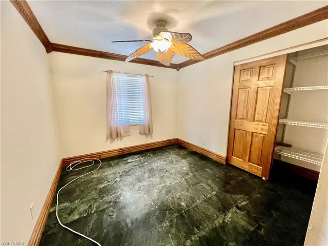 Guest bedroom with ceiling fan, baseboards, and ornamental molding