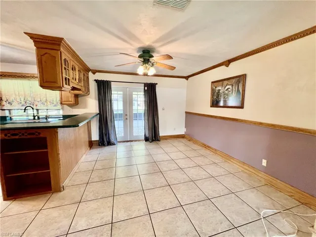Dining room with crown molding, ceiling fan, and French doors