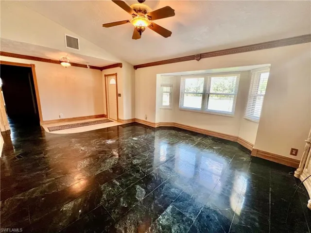 Living room with marble floors, a ceiling fan, ornamental molding, and cathedral ceilings.