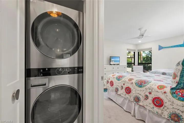 Laundry room with light carpet, stacked washer / dryer, and a ceiling fan