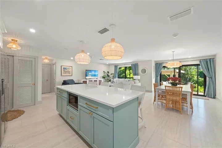 Kitchen featuring open floor plan, a kitchen bar, a center island, pendant lighting, and black microwave