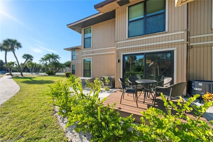 Rear view of property featuring a yard, a wooden deck, and outdoor dining area
