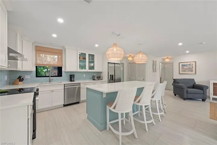 Kitchen featuring open floor plan, appliances with stainless steel finishes, a kitchen island, a kitchen bar, and pendant lighting
