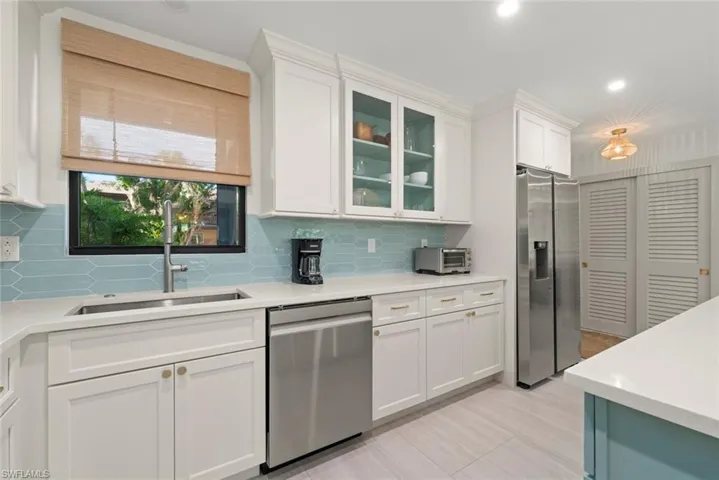 Kitchen featuring appliances with stainless steel finishes, white cabinetry, light stone counters, glass insert cabinets, and recessed lighting