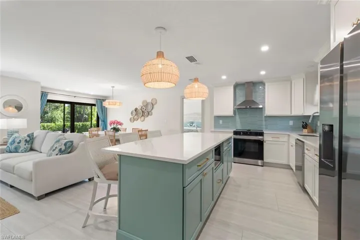 Kitchen featuring a kitchen bar, white cabinetry, appliances with stainless steel finishes, green cabinetry, and recessed lighting