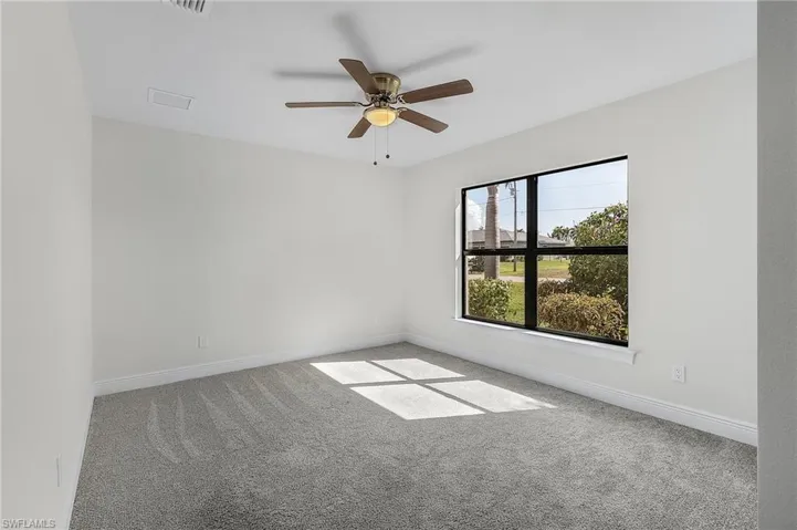 Carpeted spare room featuring ceiling fan