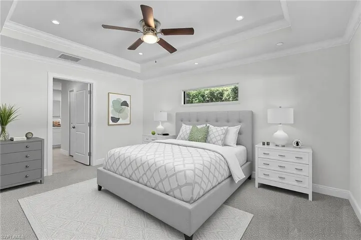Bedroom with carpet floors, ornamental molding, ceiling fan, and a raised ceiling