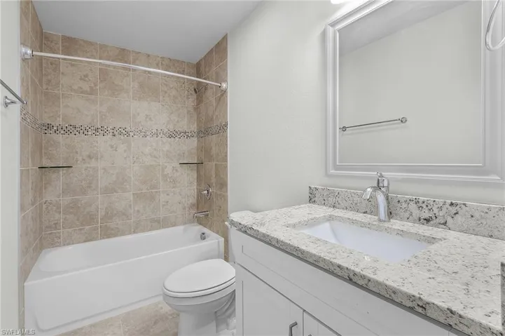 Full bathroom featuring tiled shower / bath combo, tile patterned floors, vanity, and toilet