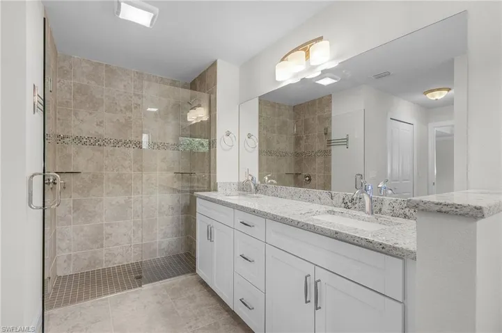 Bathroom featuring tile patterned floors, vanity, and an enclosed shower