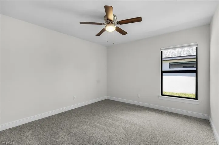 Carpeted spare room featuring ceiling fan
