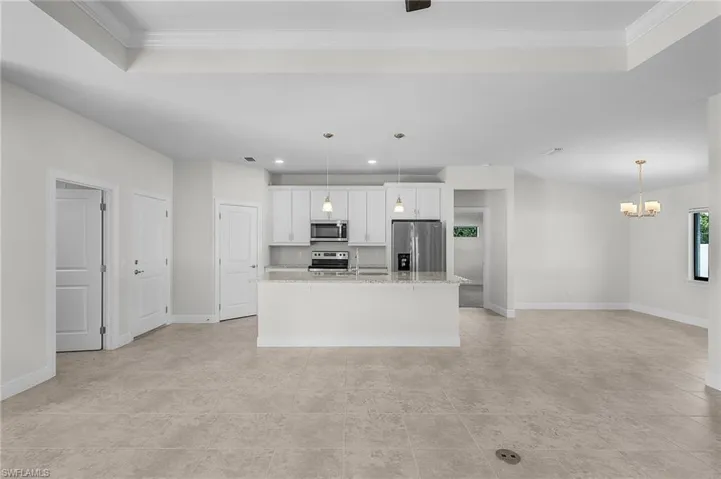 Kitchen featuring white cabinets, a center island, stainless steel appliances, and hanging light fixtures